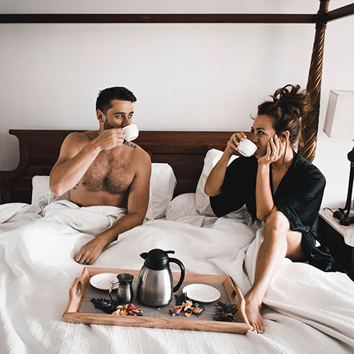 Pausa durante il sesso: coppia che beve un caffè a letto