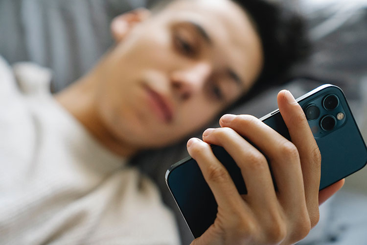 Ragazzo dipendente da porno di fronte allo smartphone sul letto