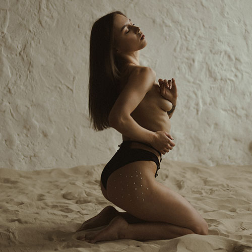 Una ragazza in topless sulla sabbia